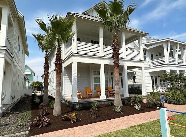 A white house with palm trees in front of it.