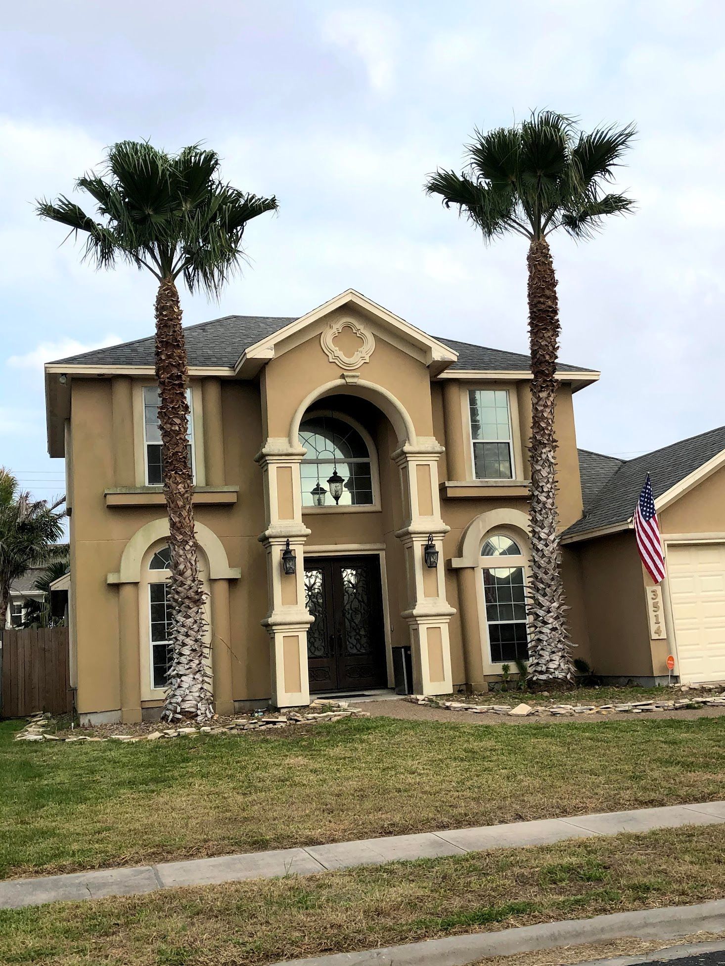 A large house with two palm trees in front of it.