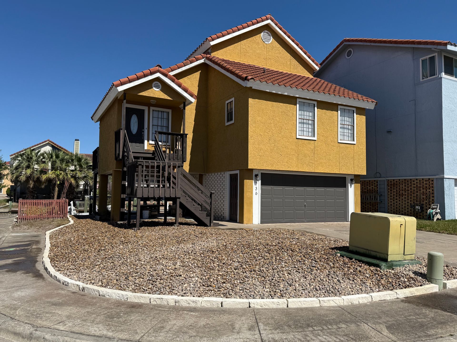 A yellow house with a balcony and a garage