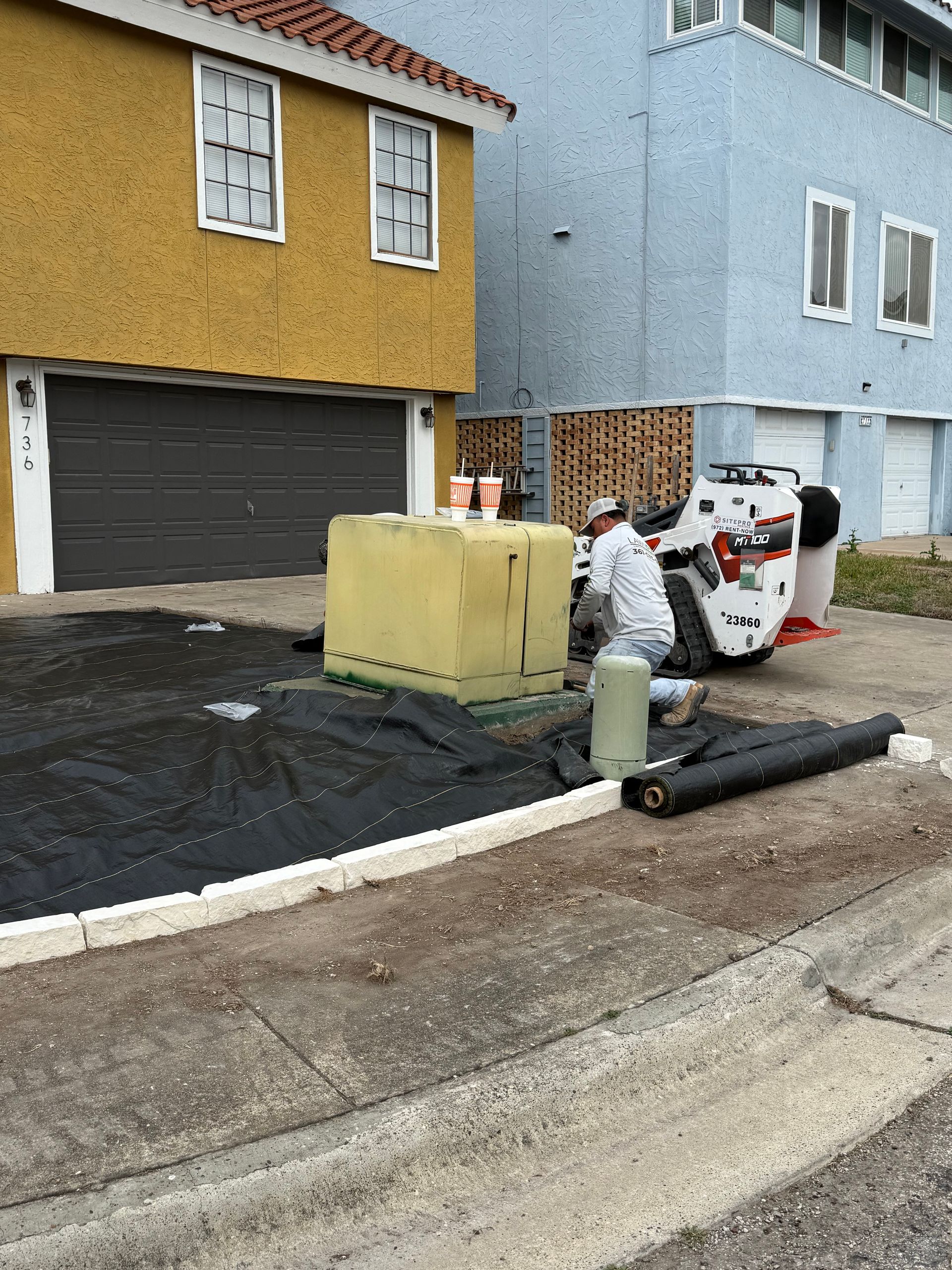 A man is working on a driveway in front of a house.
