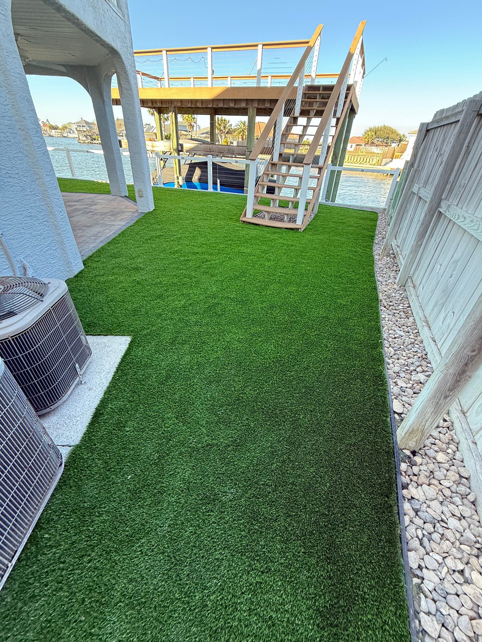 A lawn with a deck and stairs in the background.