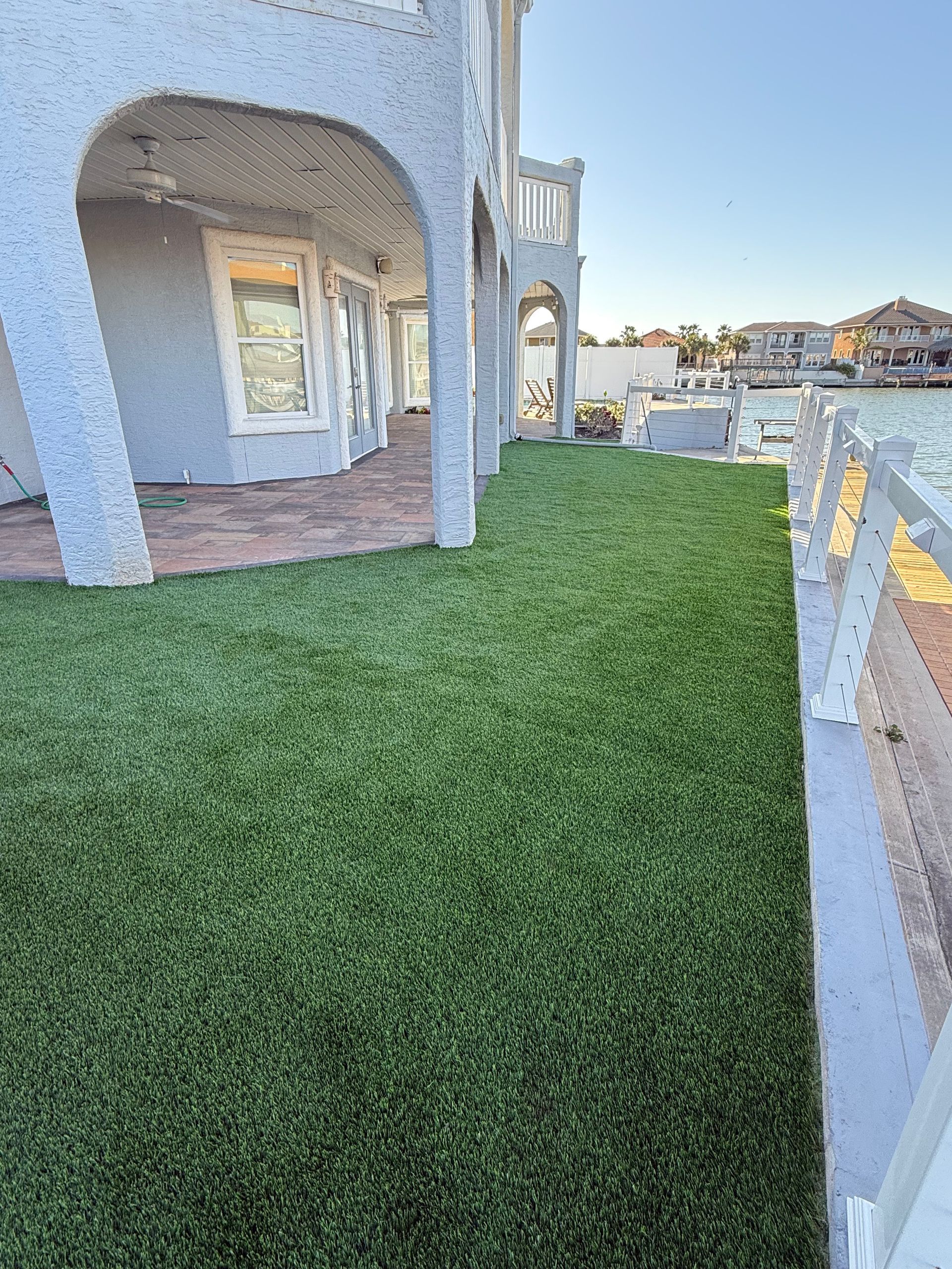 A large lawn in front of a house next to a body of water.