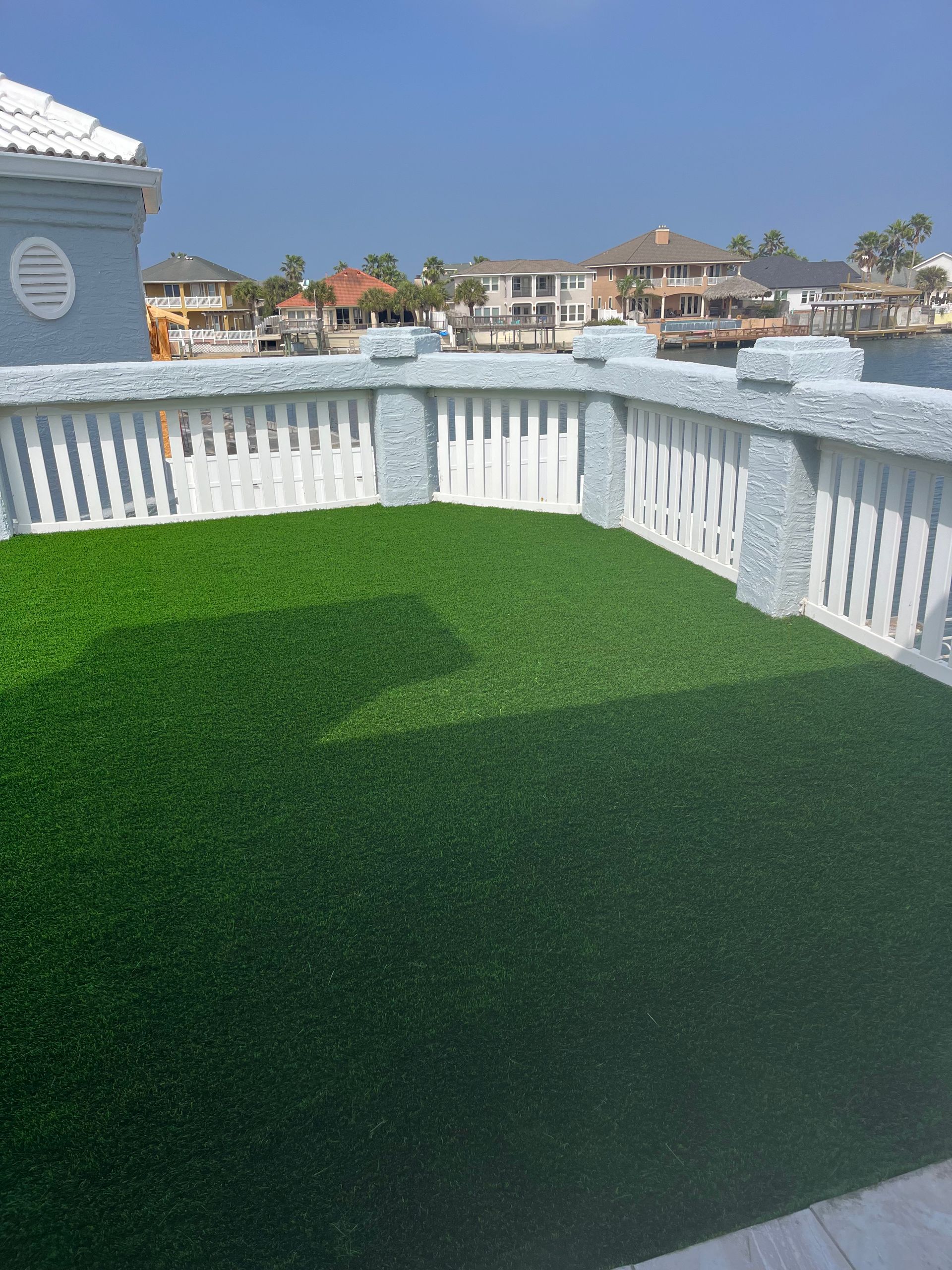 A balcony with a lot of green grass and a white railing