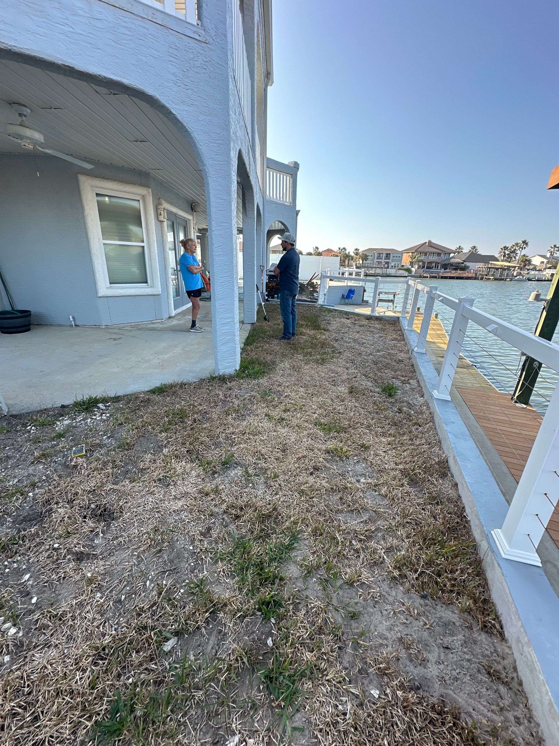 A man is standing in front of a house next to a body of water.