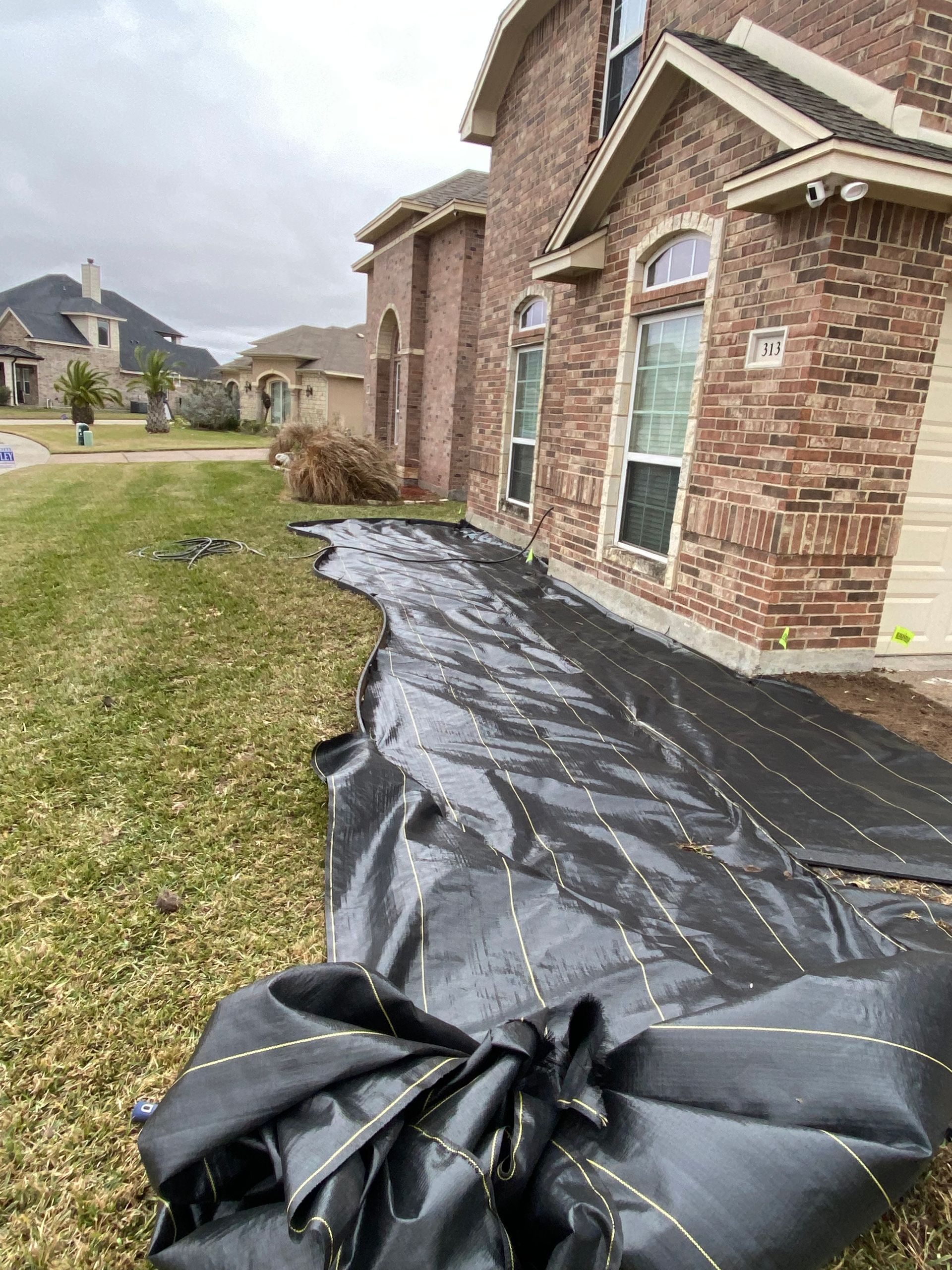 A black tarp is sitting in front of a brick house.