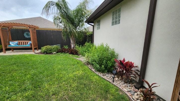 The backyard of a house with a lush green lawn and a pergola.