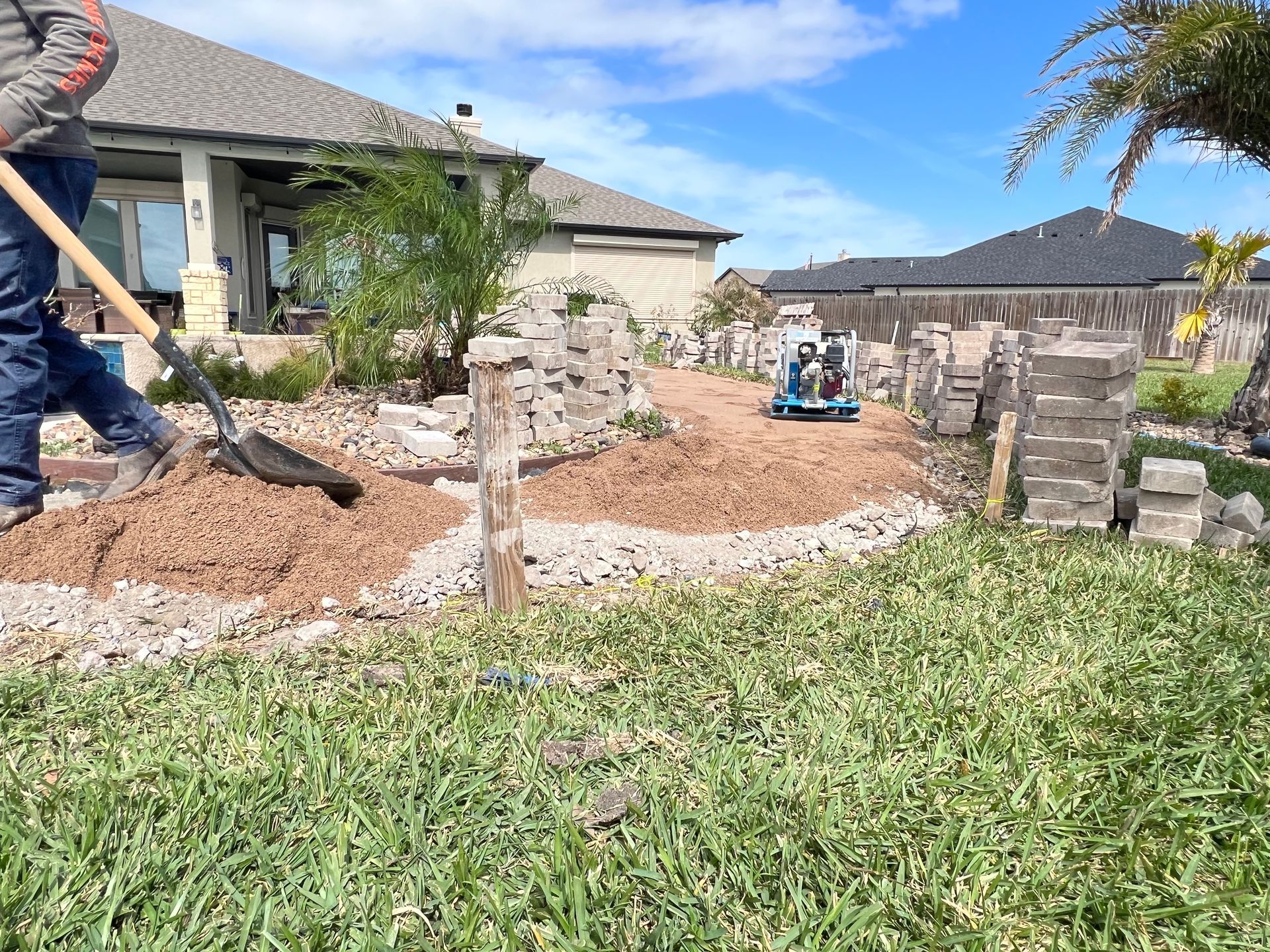 A man is digging in the grass with a shovel in front of a house.