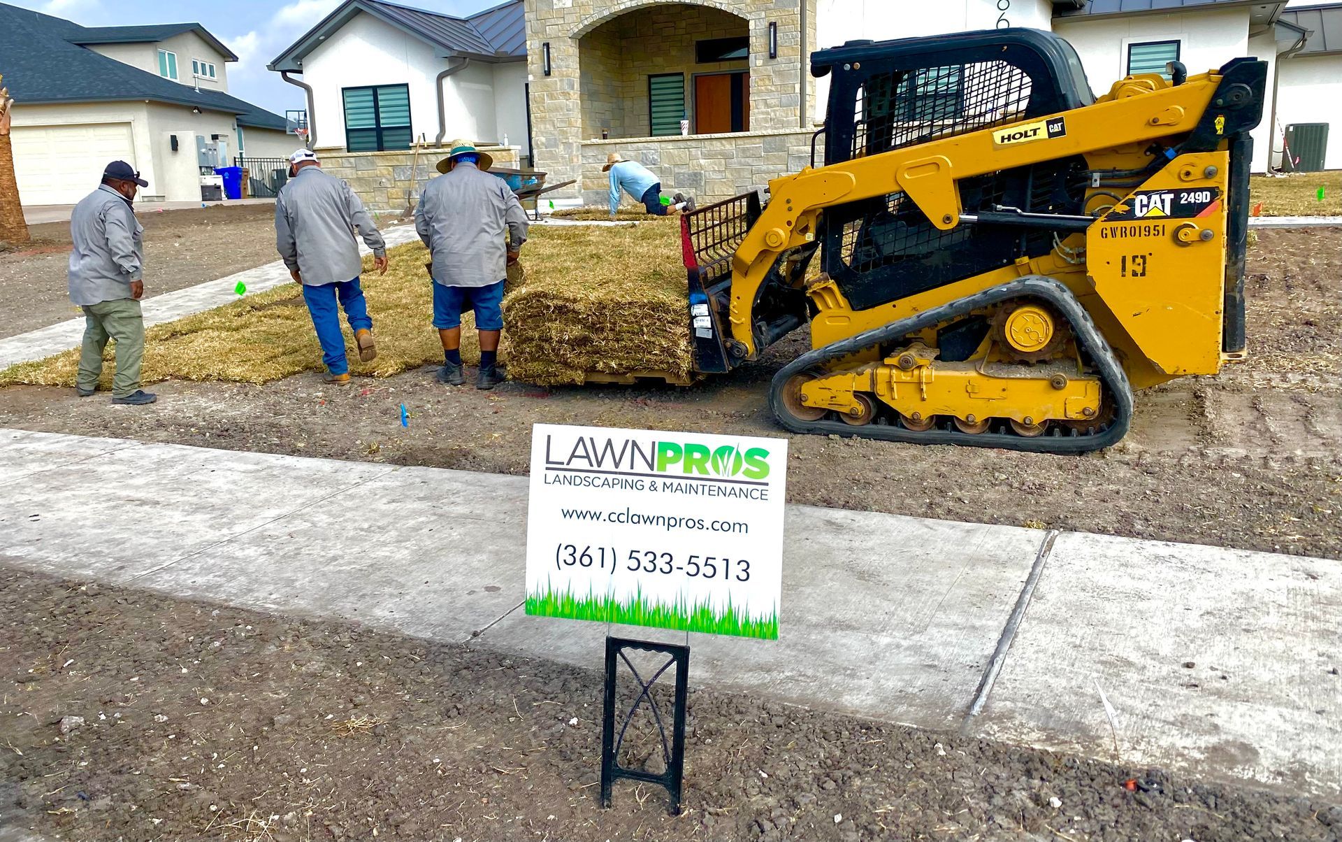 A group of men are working on a lawn in front of a house.