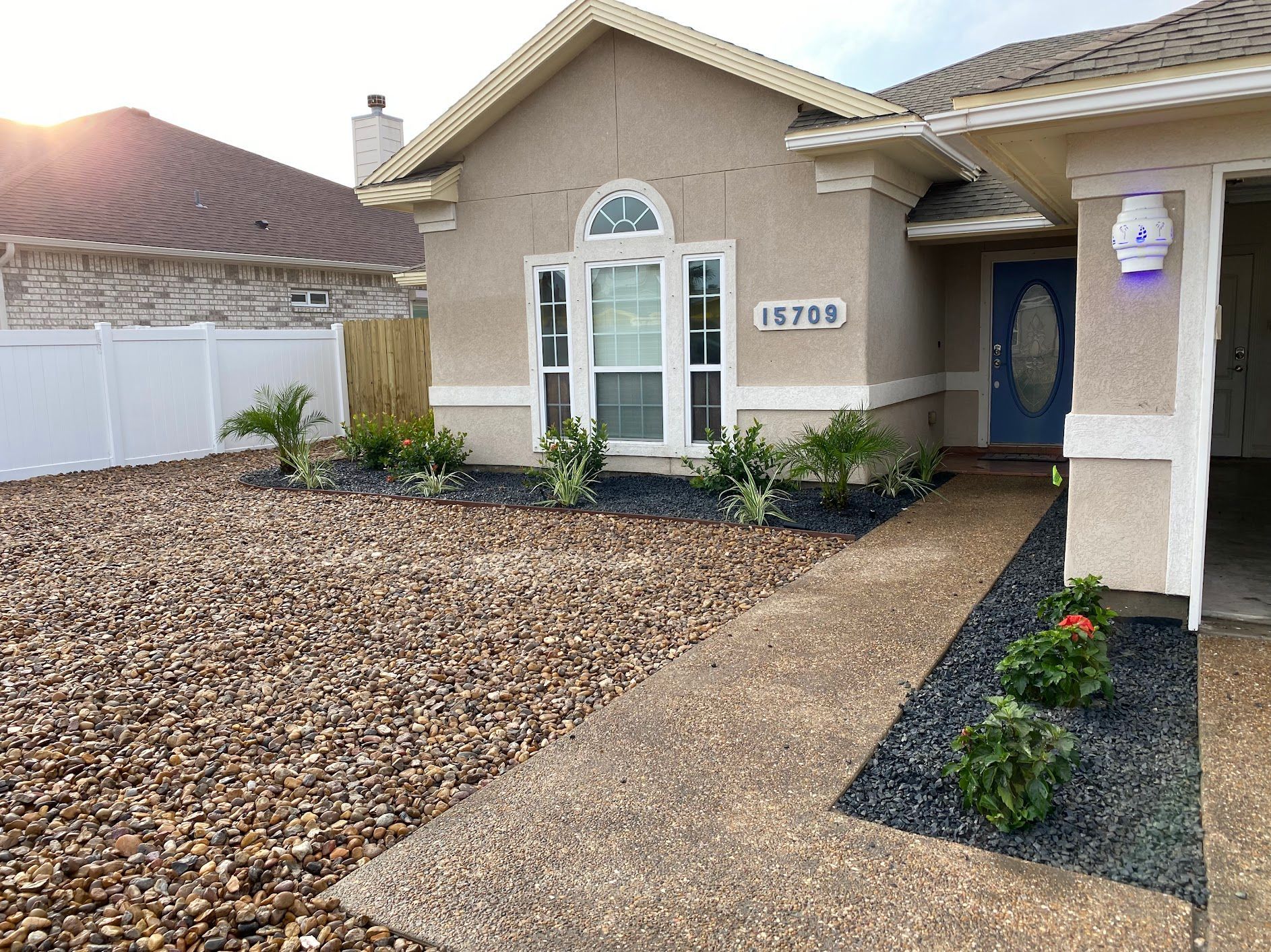 A house with a blue door and a gravel driveway in front of it.