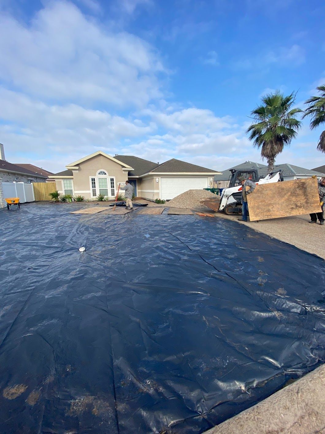 A large black tarp is covering a driveway in front of a house.