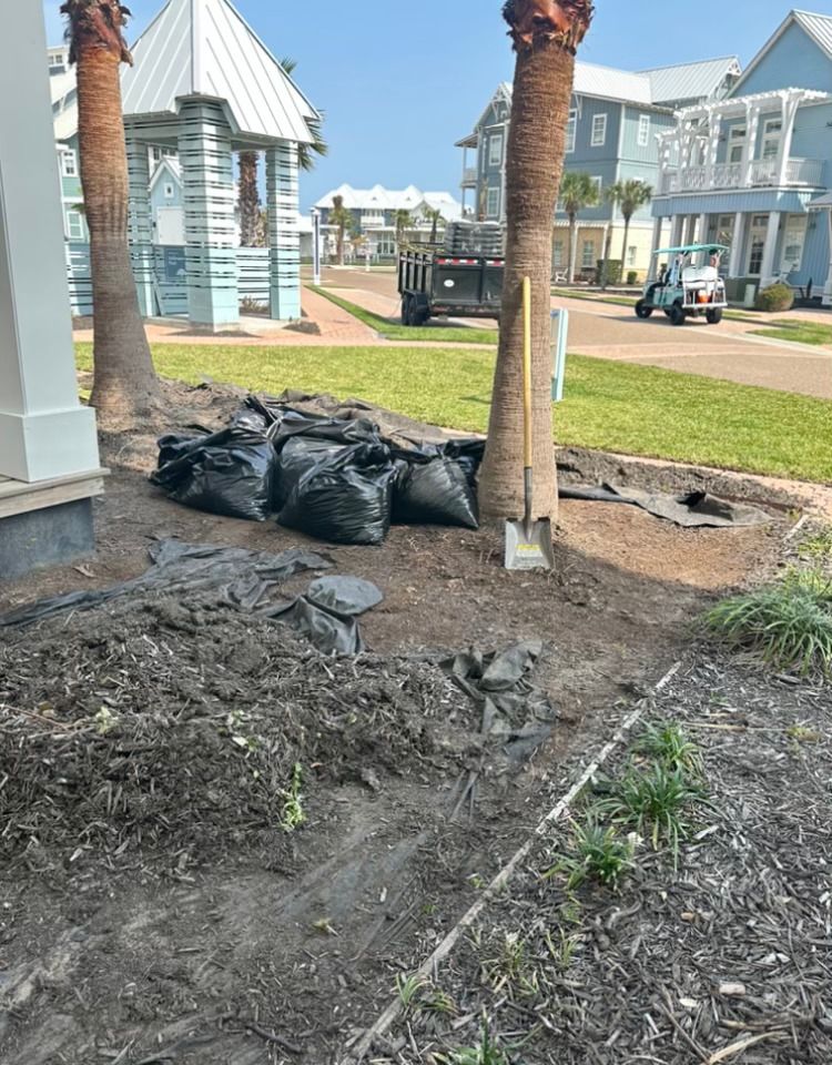 A bunch of bags of dirt are sitting on the ground in front of a house.