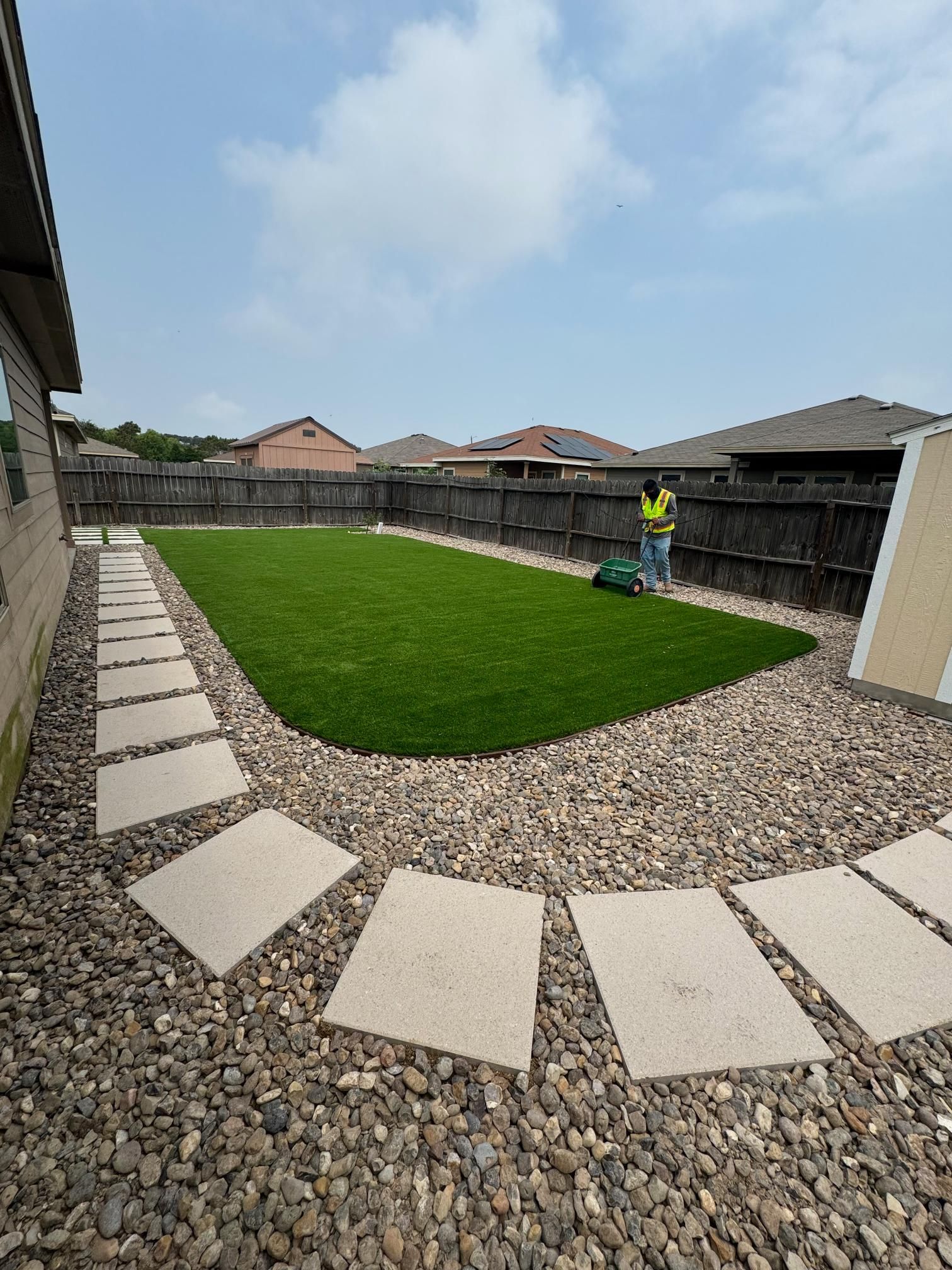 A man is cutting grass in a backyard with a lawn mower.
