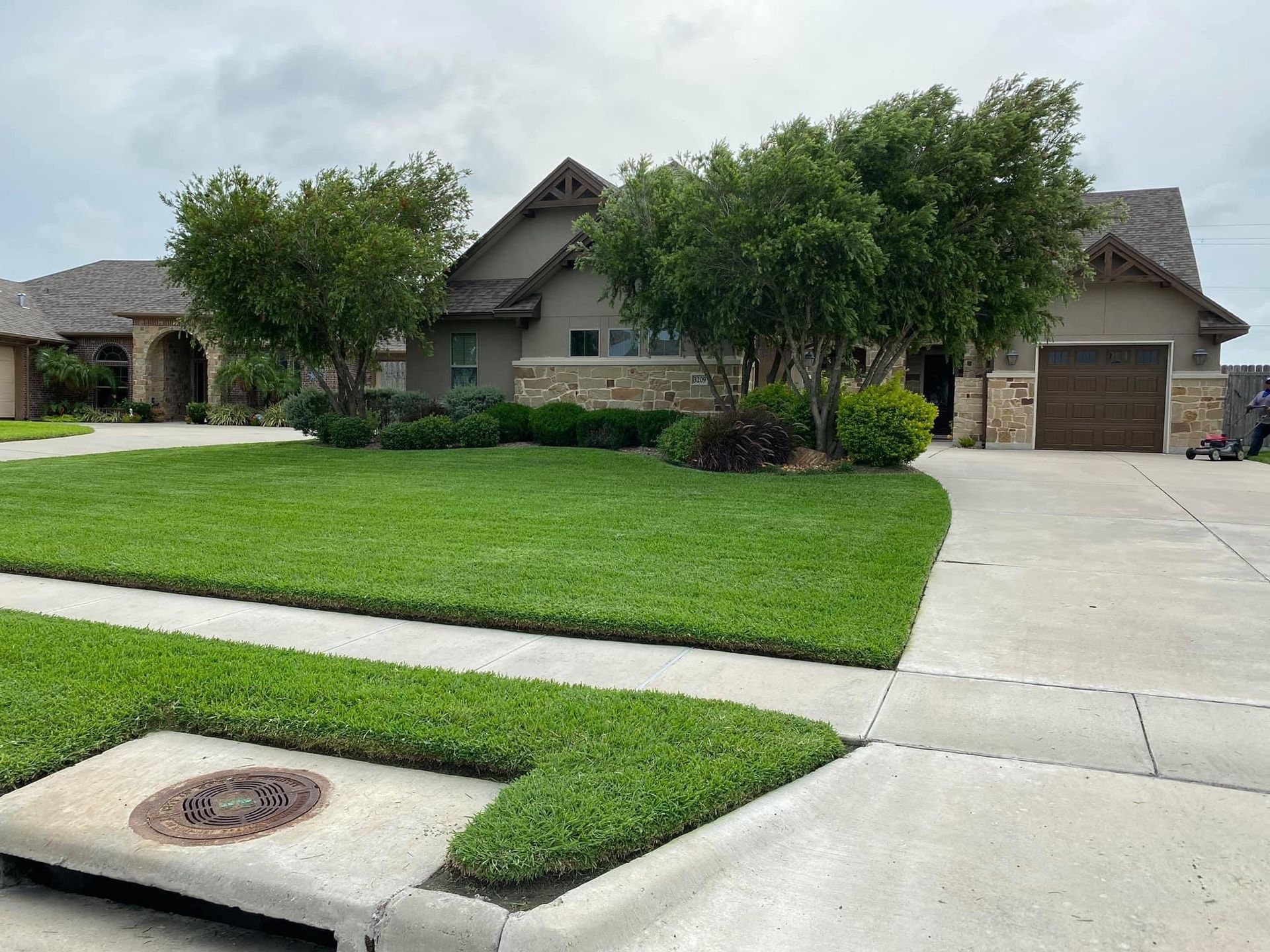 A large house with a lush green lawn and trees in front of it.