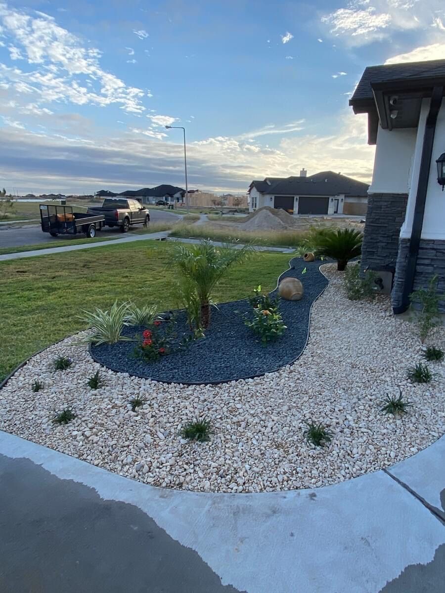 A gravel garden in front of a house with a truck parked in the background.