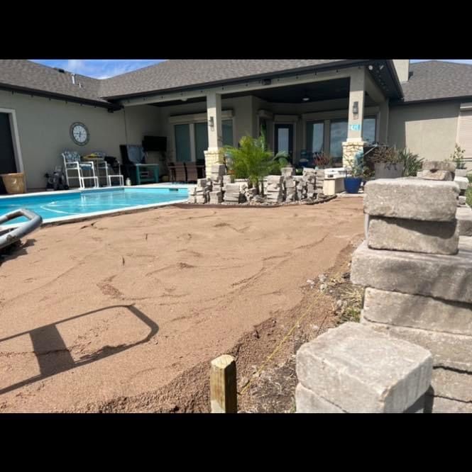 A stack of bricks is sitting in front of a house next to a pool.
