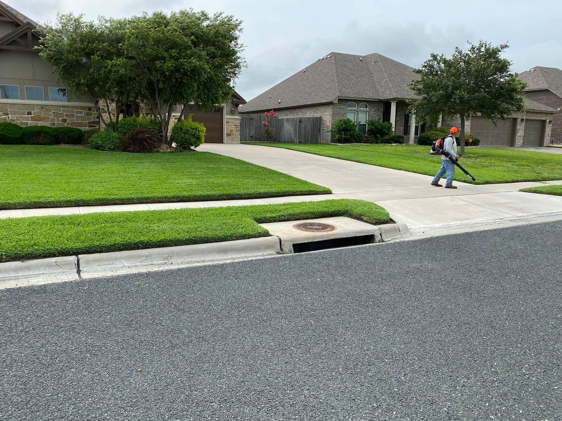 A man is using a lawn mower to cut the grass in front of a house.