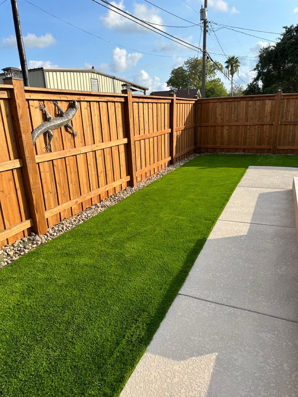 A backyard with a wooden fence and artificial grass.
