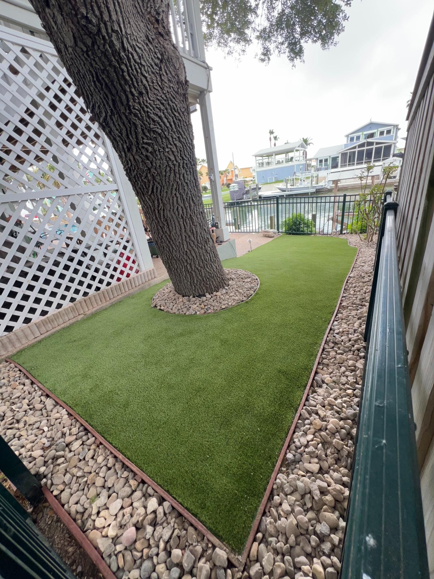There is a tree in the middle of a lush green lawn.