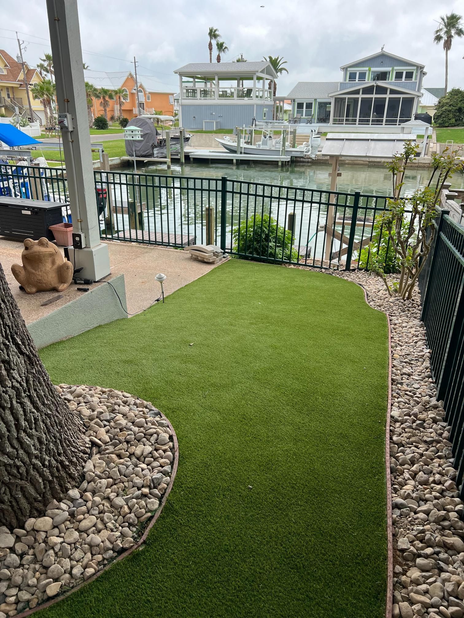 A lawn with a fence and a boat in the background.