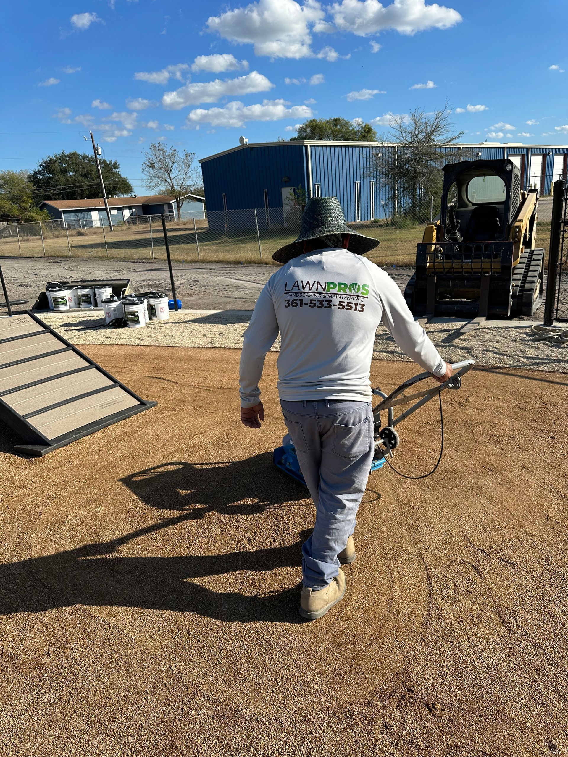 A man wearing a hat and a white shirt is walking on a dirt road.