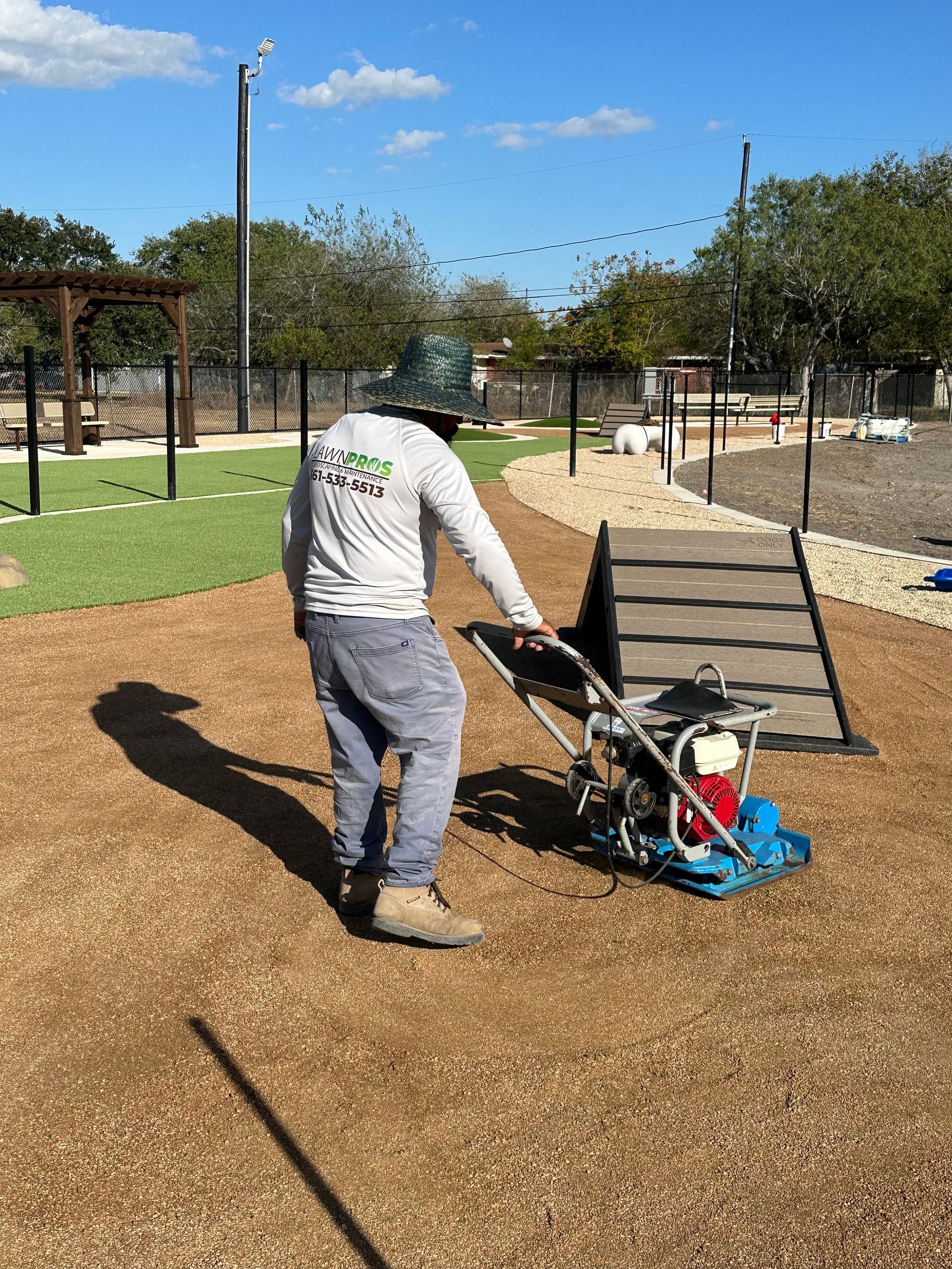 A man is working on a playground with a machine.