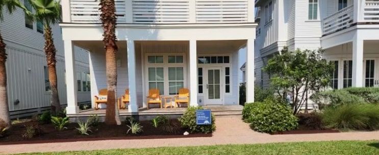 A white house with a porch and chairs on it