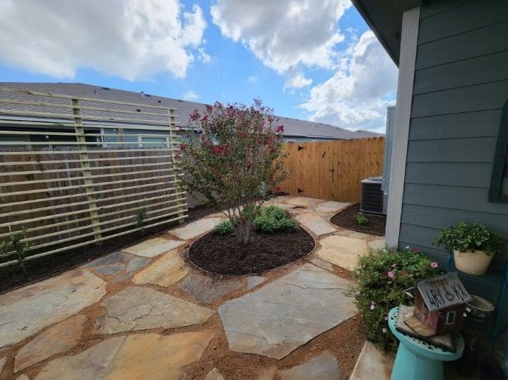 A stone patio with a tree in the middle of it in front of a house.