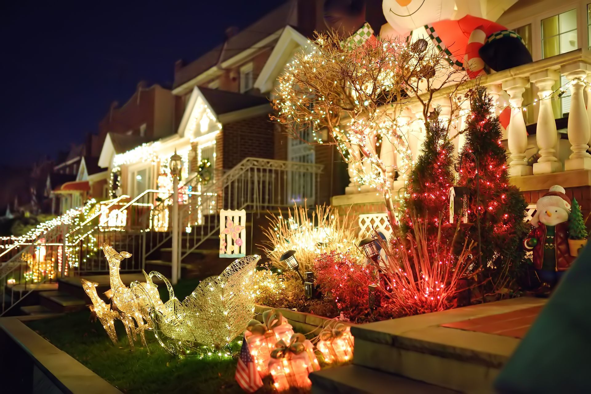 Houses decorated with colorful Christmas lights at night.