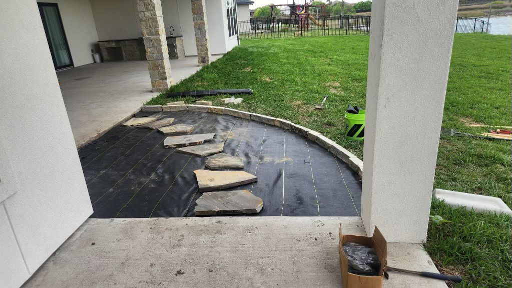 A box of rocks is sitting on the sidewalk in front of a house.