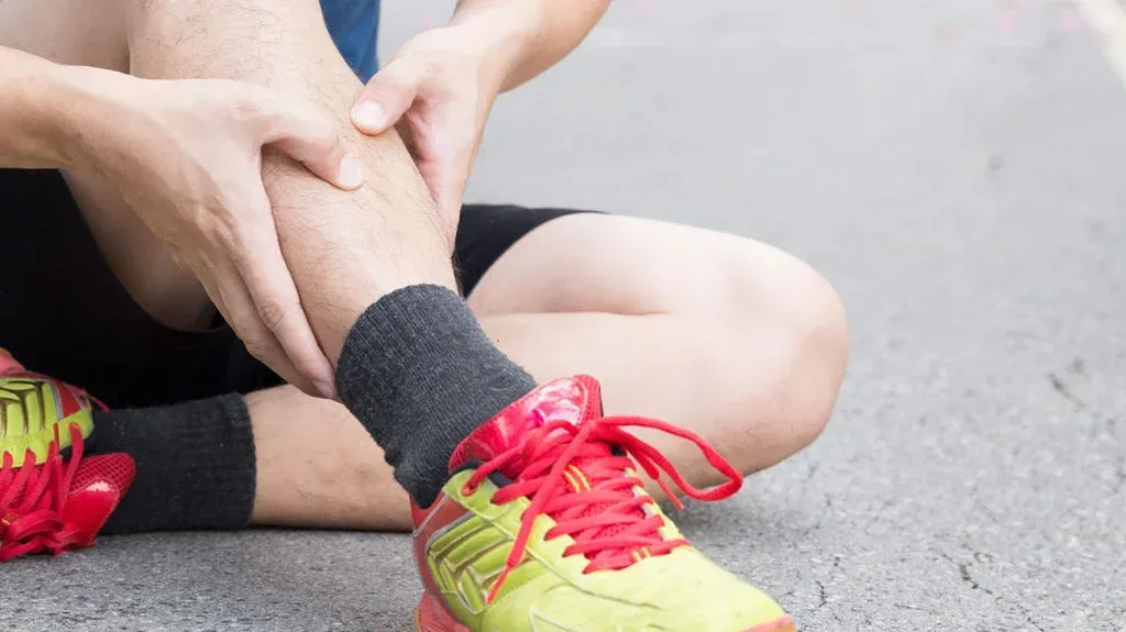 person holding shin in pain