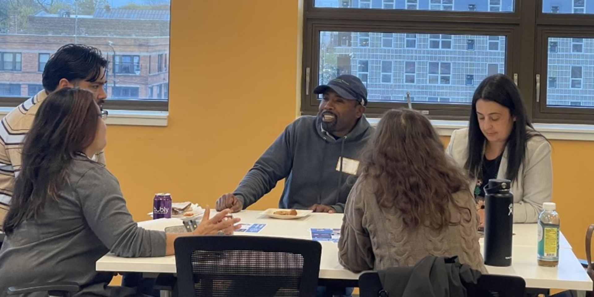 A group of people are sitting around a table talking to each other.