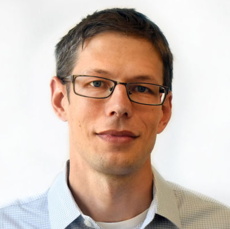 A man wearing glasses is smiling for the camera