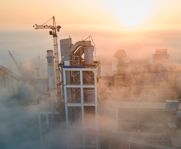 An aerial view of a factory in the fog at sunset.
