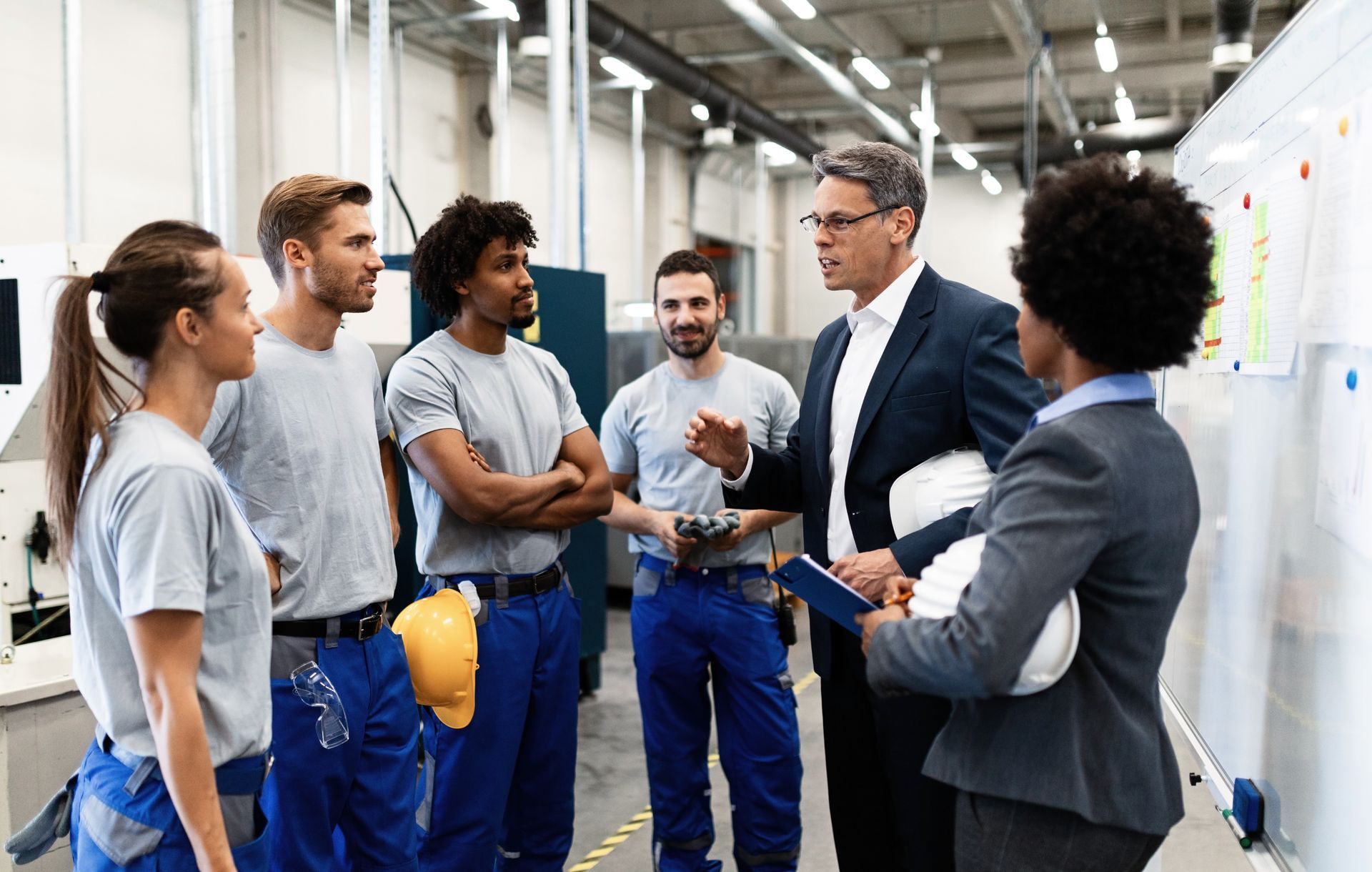 A group of people are standing in a factory talking to each other.