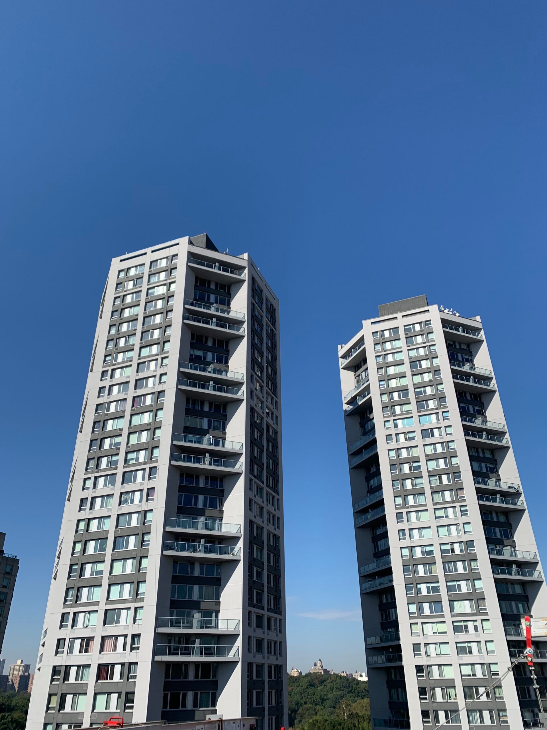 Two tall buildings are against a blue sky on a sunny day.