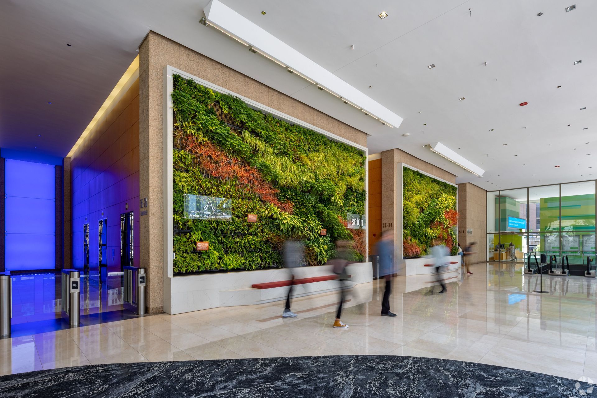 A lobby with a large green wall and people walking around.