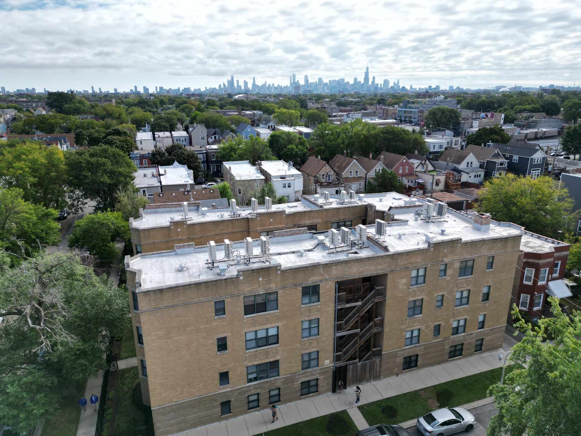 An aerial view of a large brick building with a city skyline in the background.