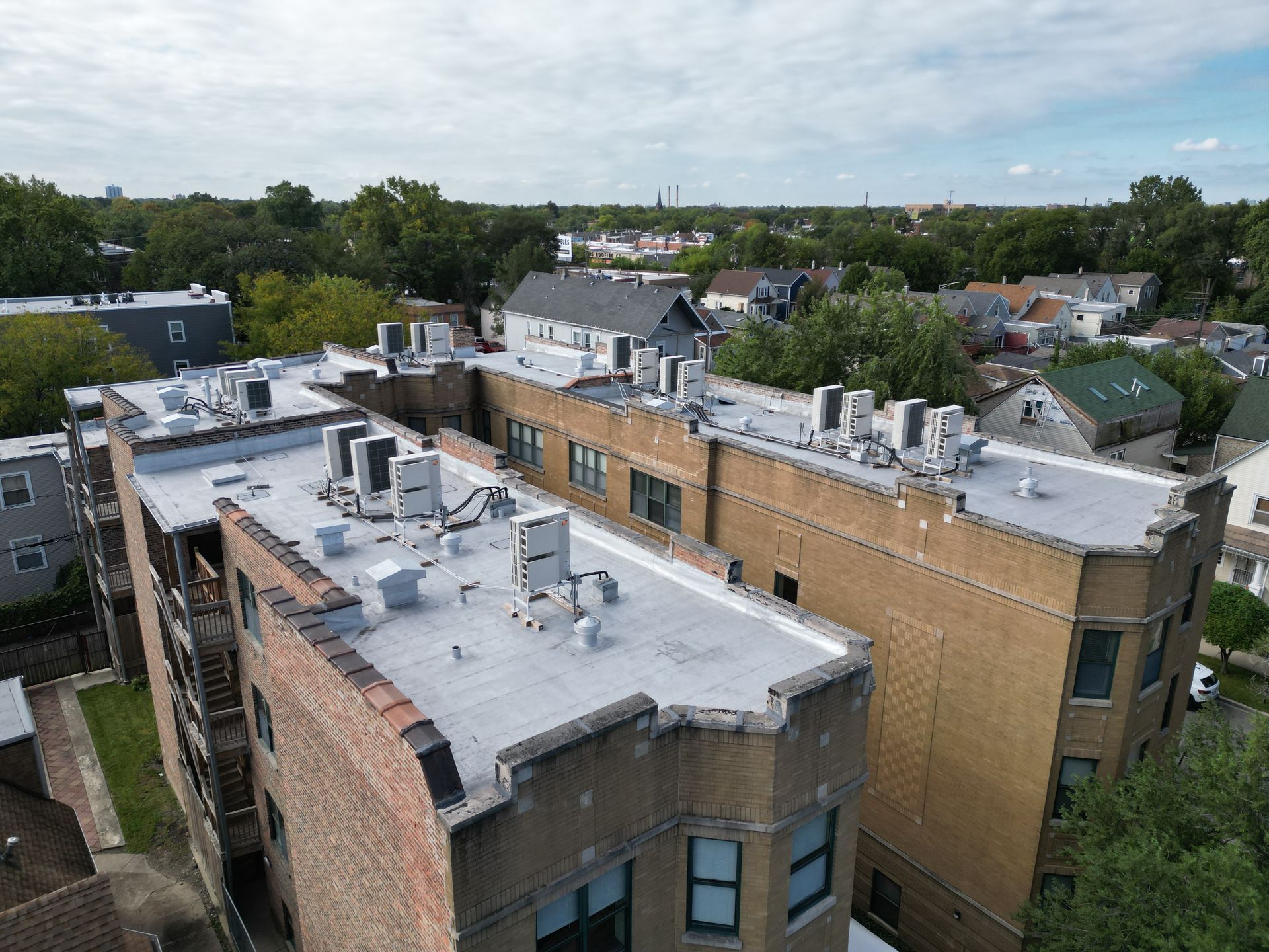 An aerial view of a brick building with a white roof.