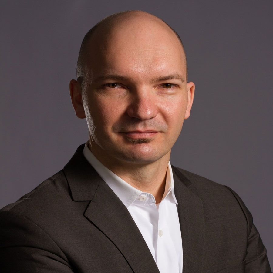 A bald man is wearing a suit and white shirt