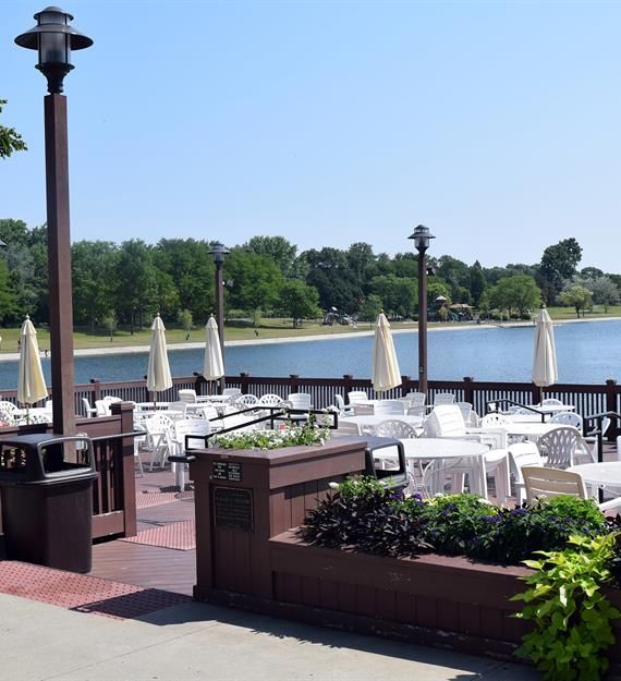 A patio with tables and chairs overlooking a lake