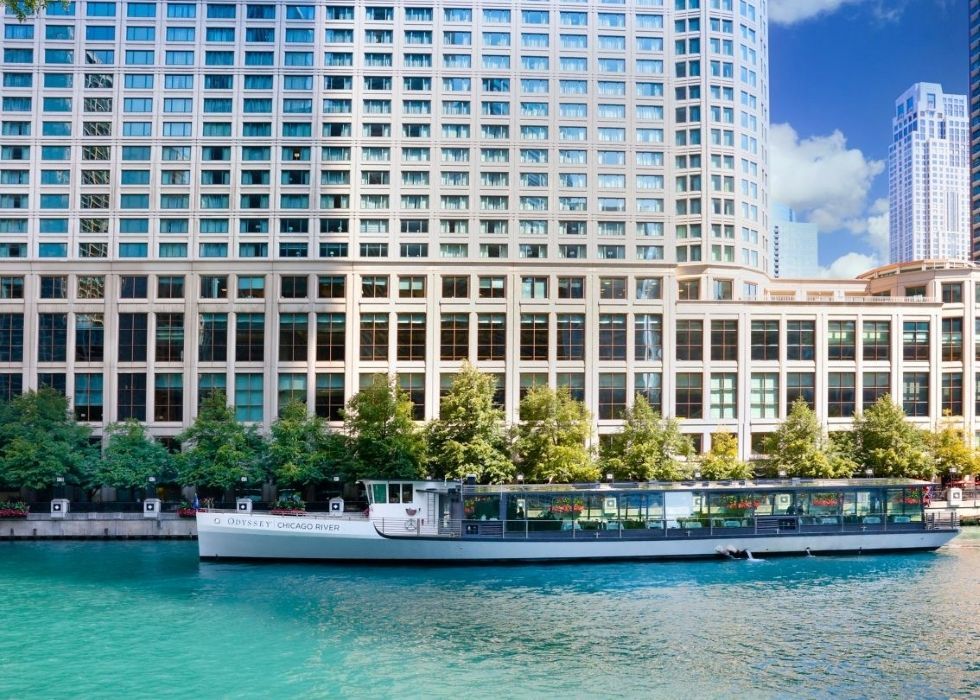 A boat is floating on a river in front of a large building.