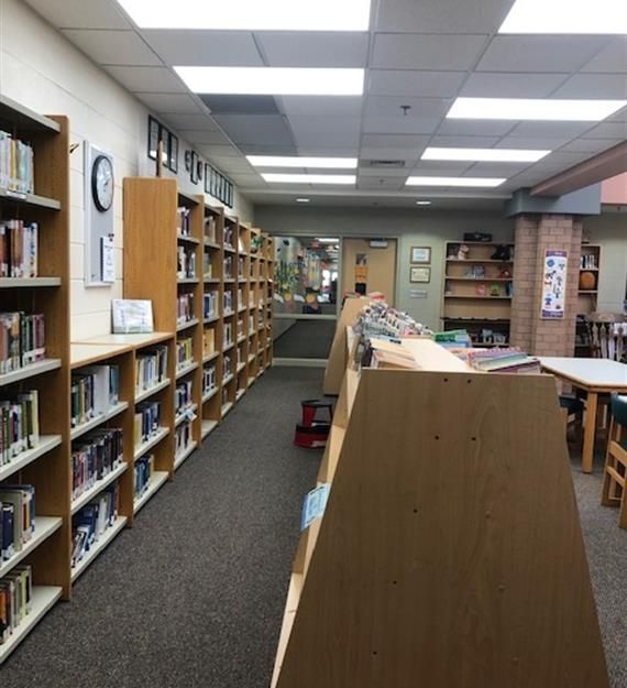 A library with lots of books on shelves and a clock on the wall