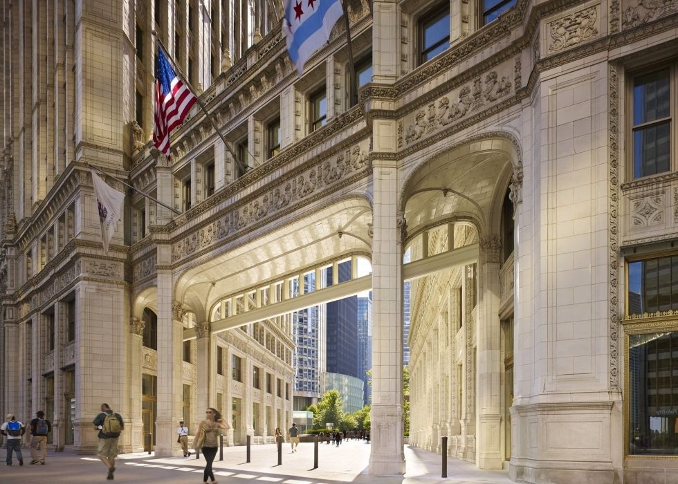 A group of people are walking down a sidewalk in front of a large building.