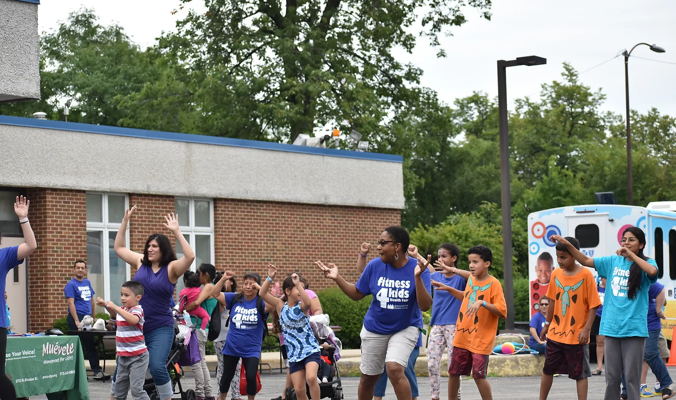 A group of children are dancing in front of a building.