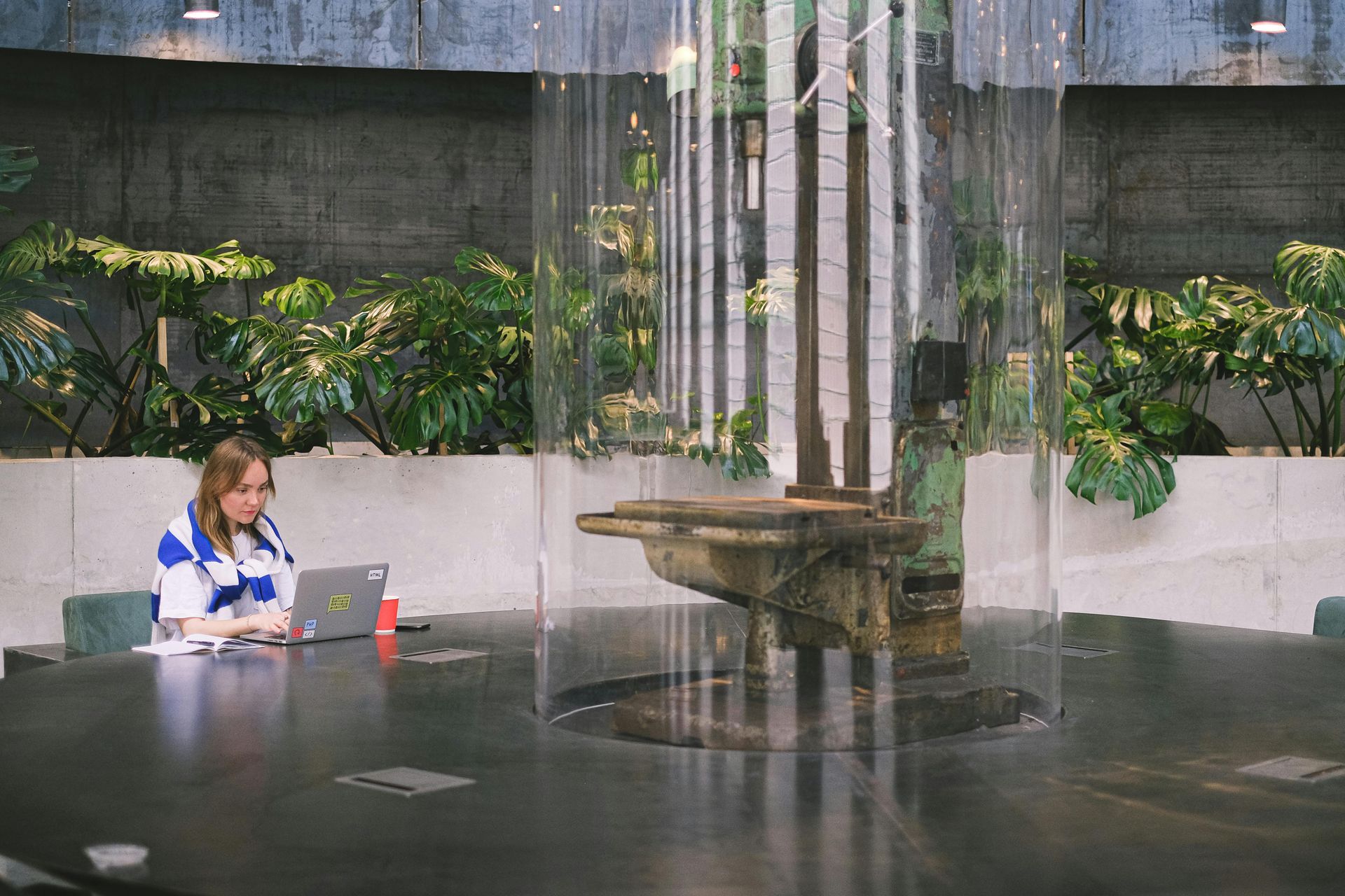 A woman is sitting at a table with a laptop in front of a fountain.