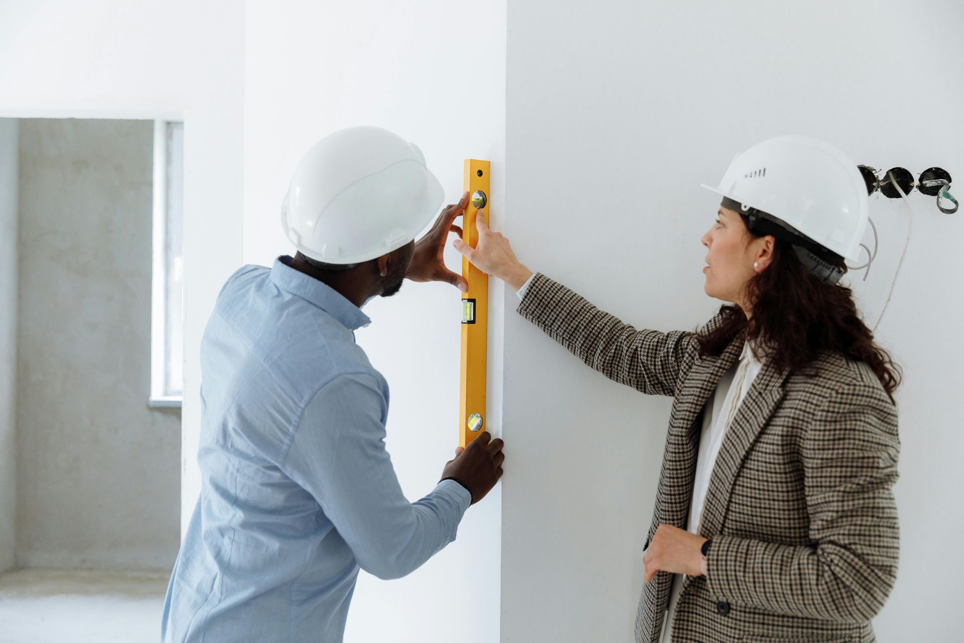 A man and a woman are measuring a wall with a level.