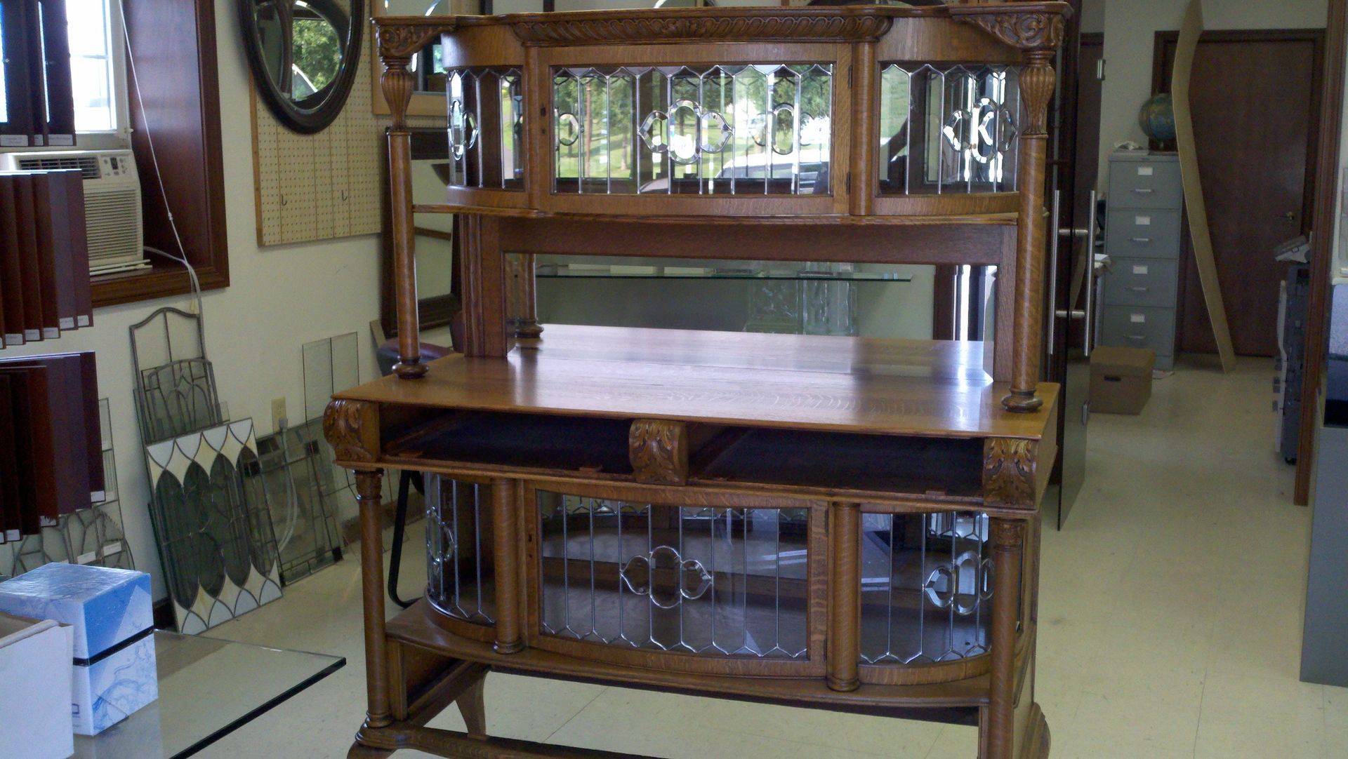 A large wooden cabinet with glass doors is sitting in a room.
