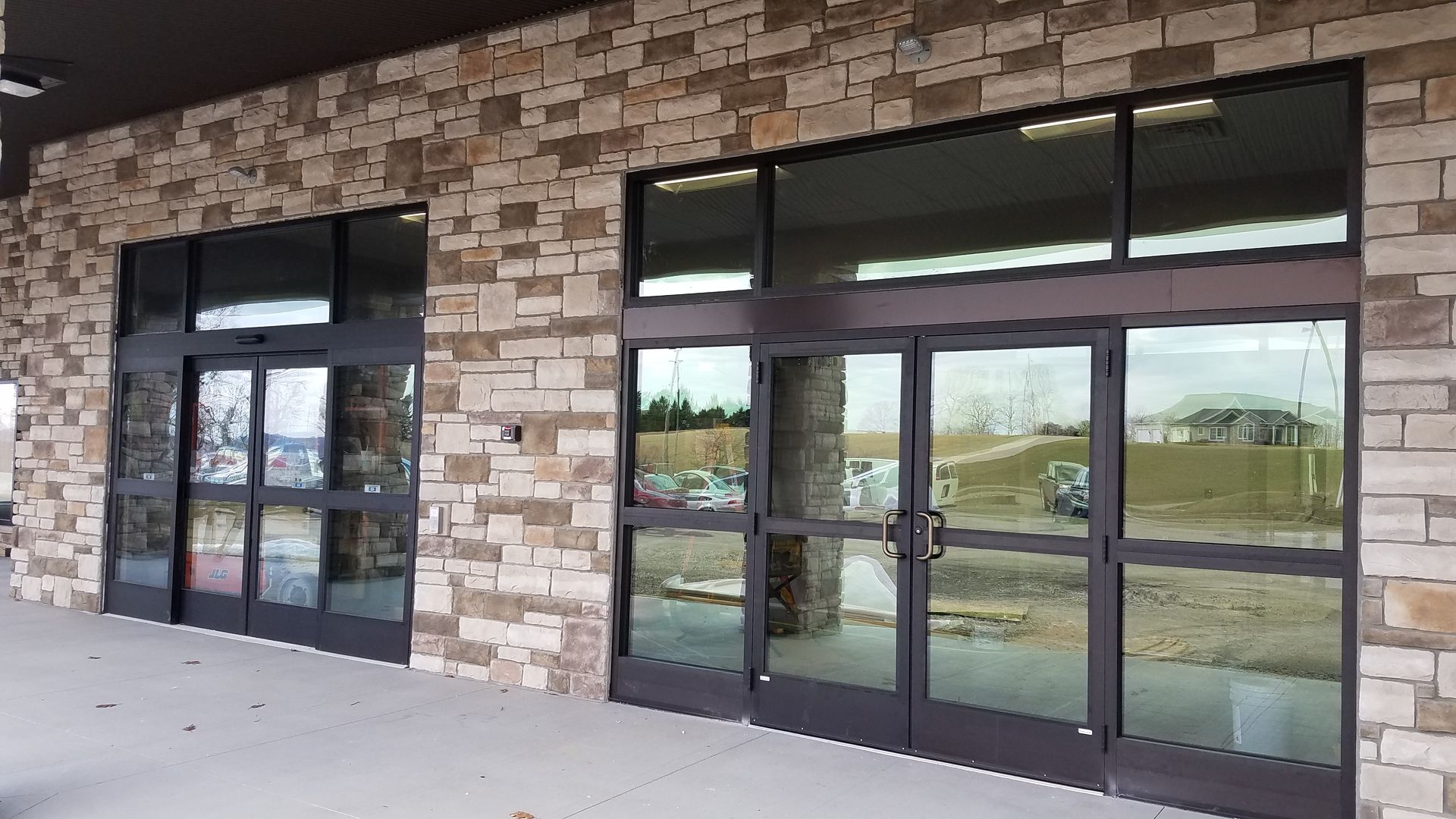 Exterior of a building with stone facade and large glass automatic doors.