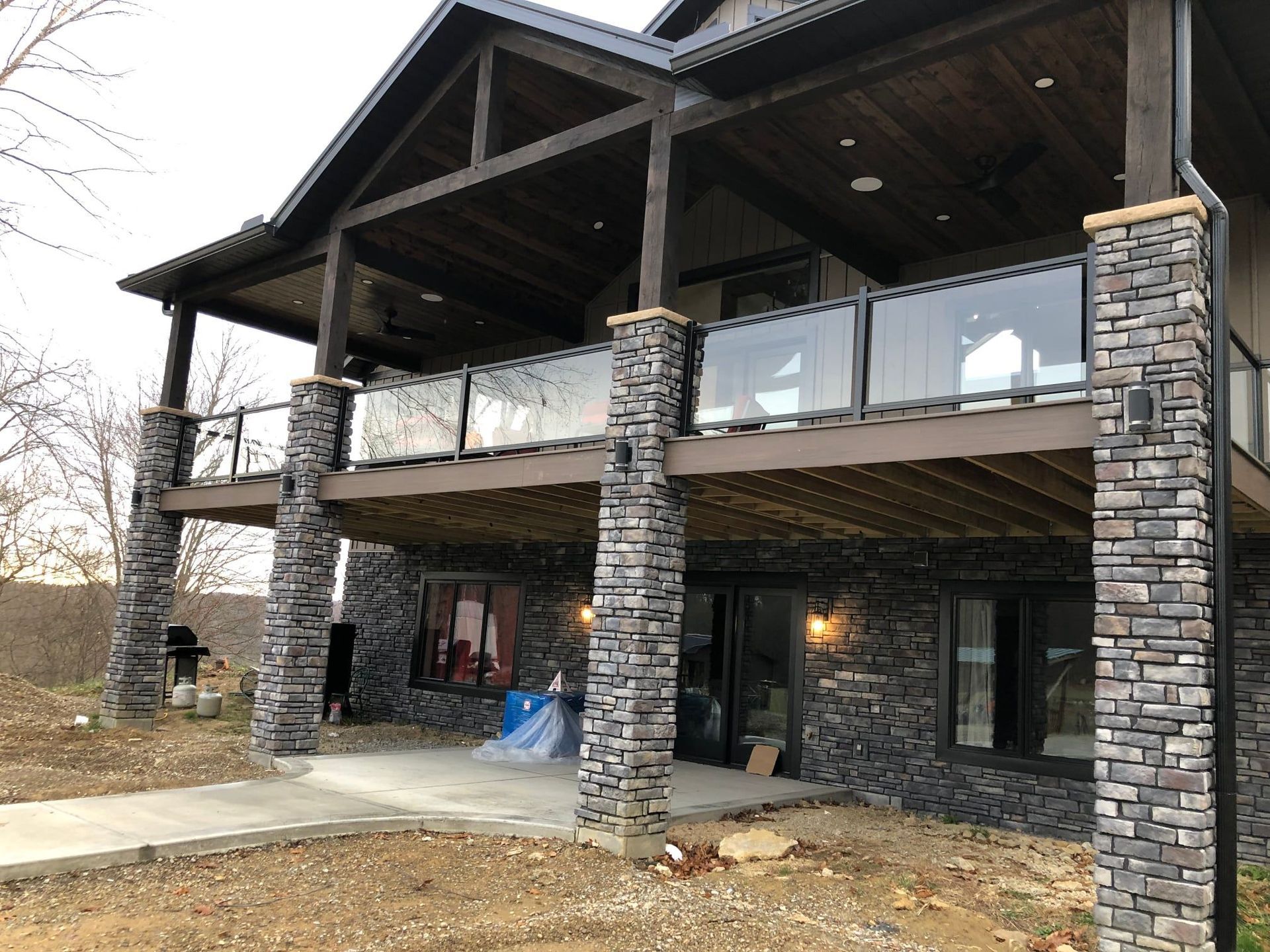 The back of a house with a large deck and stone pillars