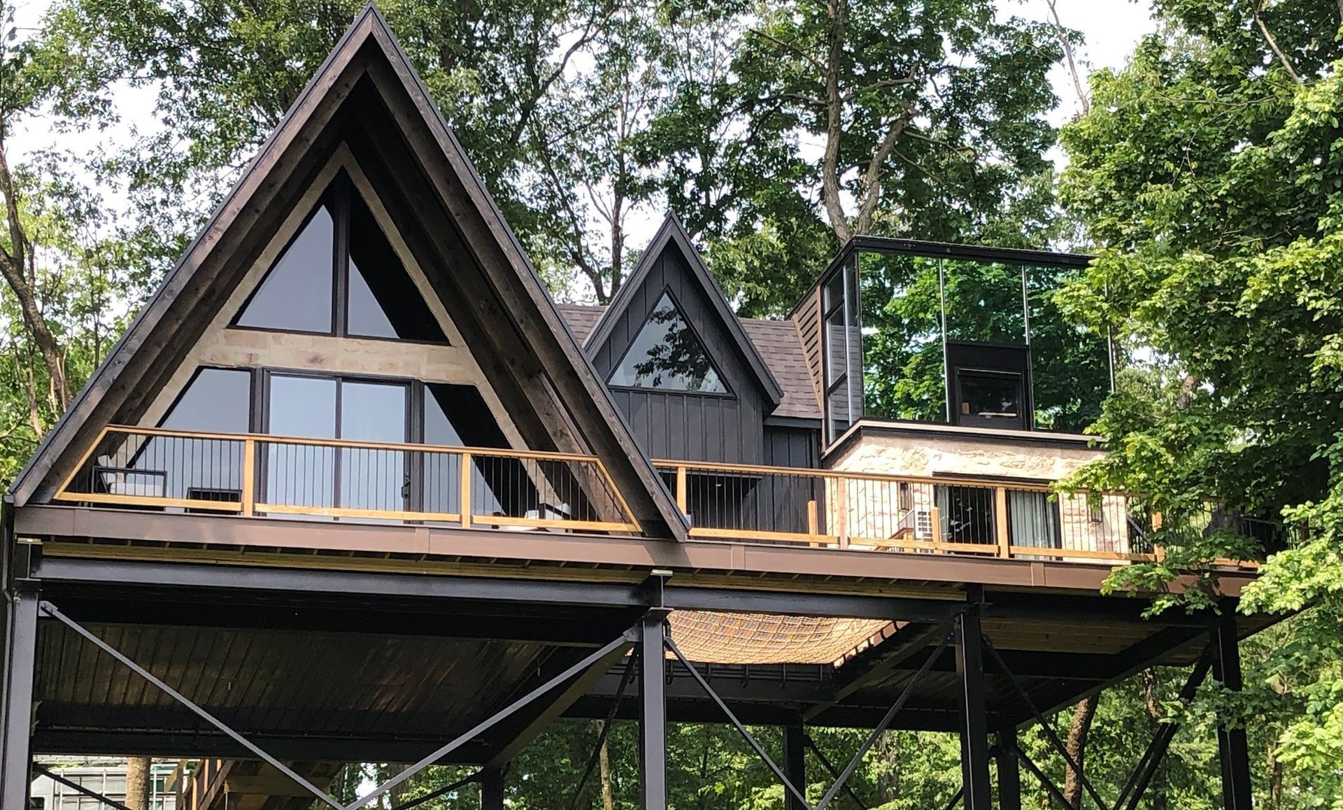 A house with a triangle shaped roof is surrounded by trees.